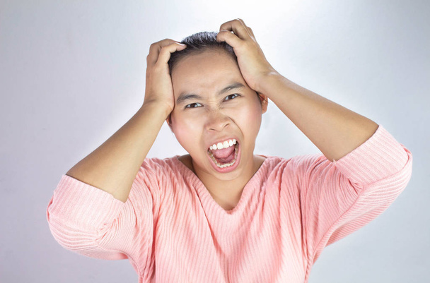 Retrato de una mujer estresada sosteniendo la cabeza en las manos y grita fuertemente enojada
. - Foto, imagen