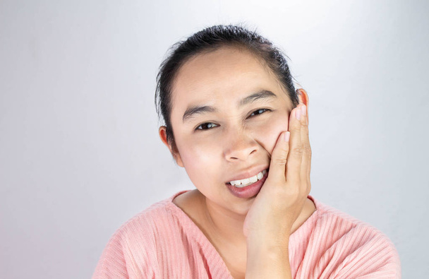 Aasialainen nainen koskettaa poskea kädellä, koska hän kärsii hammassärystä. Hammashoidon ja terveydenhuollon käsite
. - Valokuva, kuva