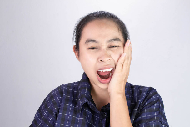 Mujer asiática tocando la mejilla con la mano porque está sufriendo de dolor de muelas. Cuidado dental y concepto de salud
. - Foto, imagen