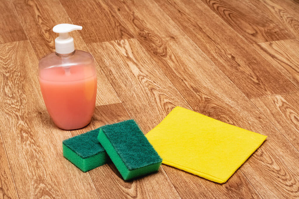 Agente de limpeza, esponja e pano amarelo no chão de madeira
 - Foto, Imagem