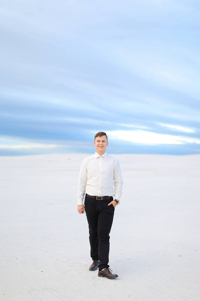 Young european man standing in winter steppe and wearing white shirt. - Фото, изображение