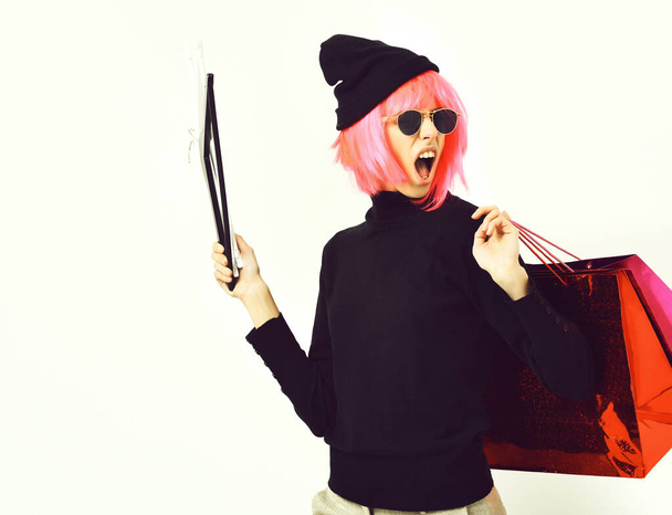 fashionable sexy girl in pink wig holding package with hangers - Foto, afbeelding