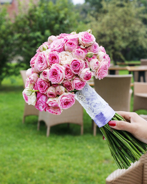 Frau hält einen Brautstrauß aus winzigen rosa Rosen in der Hand. - Foto, Bild