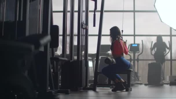 Intensive training at the morning in gym. Training in a room with large Windows in the background a woman uses an ellipsoid and a treadmill - Footage, Video