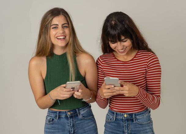 Happy girl friends sending messages on mobile phone chatting in social media app or shopping online. Two women having fun together using smart phones. People, lifestyle, communication and technology. - Foto, immagini