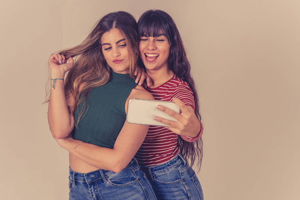 Two beautiful happy girlfriends taking selfies or recording video for blog on social media. Selfie of two beautiful women together having fun. People, technology, friendship and social media concept. - Photo, Image