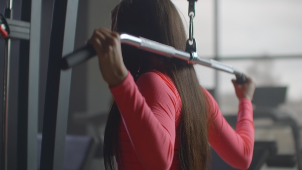 Training with a special program in the gym. Training in a room with large Windows in the background a woman uses an ellipsoid and a treadmill - Footage, Video