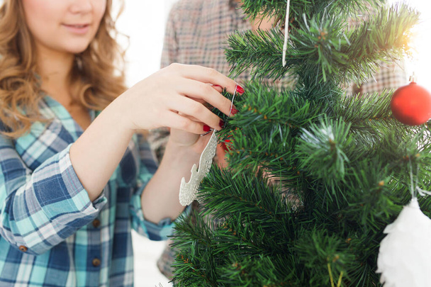 family, x-mas, winter holidays and people concept - close-up of happy young couple decorating christmas tree at home - Photo, Image