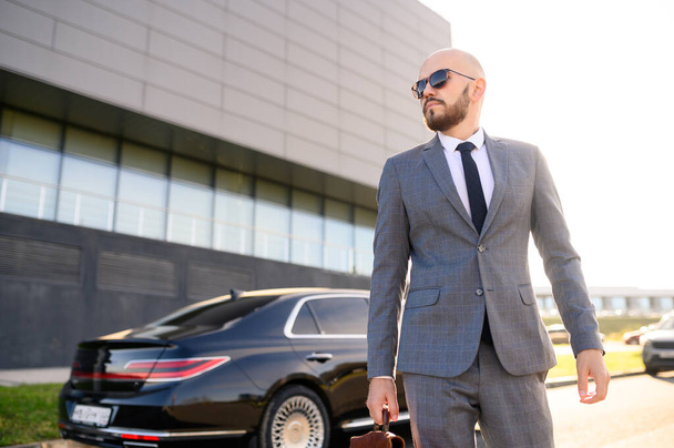  successful man in a suit with a briefcase on the background of an expensive car - Fotó, kép