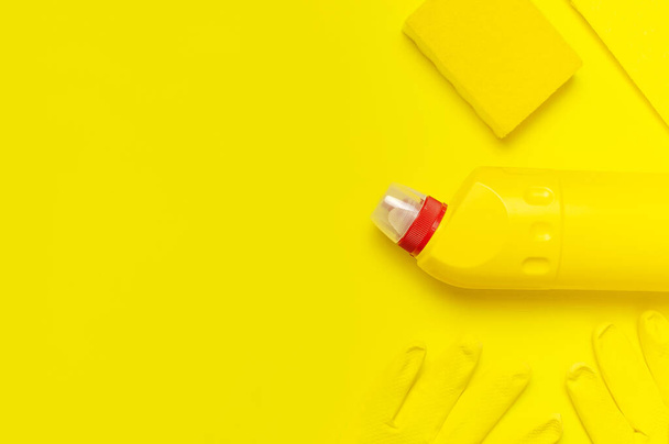 House cleaning concept. Household chemicals, disinfectant, bleach, antibacterial gel, yellow rubber gloves, sponge, rags on yellow background. Flat lay top view copy space. Cleaning accessories - Foto, Imagem