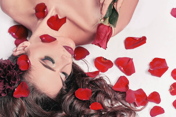young woman with rose lying among rose petals - Fotoğraf, Görsel