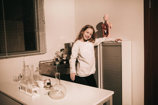 cute teen girl standing near the laboratory table - Фото, изображение