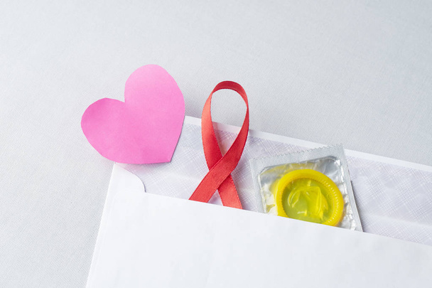 Dünya Yardım Günü için kondom destekli kırmızı kurdele, AIDS, HIV - Fotoğraf, Görsel