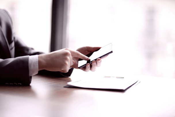 close up. businessman typing on a smartphone, sitting at the Desk - Φωτογραφία, εικόνα