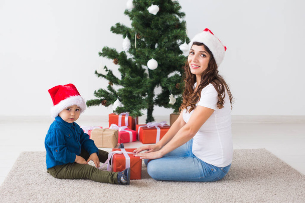 Χριστούγεννα, μόνος γονέας και έννοια των διακοπών - χαριτωμένο μικρό αγόρι κρατώντας χριστουγεννιάτικο δώρο για τη μητέρα του στο σπίτι. - Φωτογραφία, εικόνα