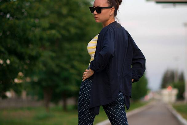 Magabiztos, napszemüveges fiatal nő a sétányon a parkban - Fotó, kép