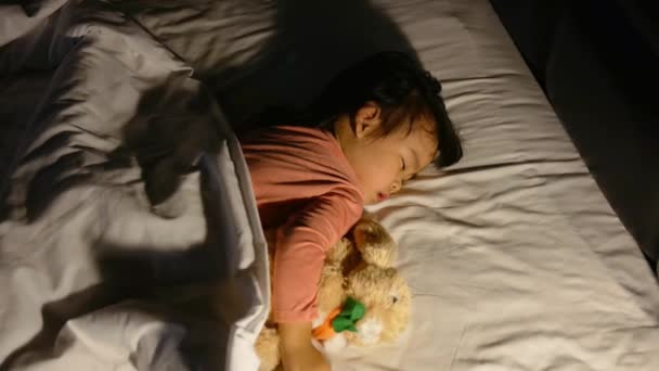 Madre asiática está poniendo manta en su hija que está durmiendo en la cama y buenas noches beso con amor. Concepto de salud
. - Metraje, vídeo