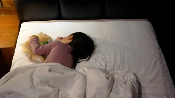Asian mother is putting blanket on her daughter who is sleeping in the bed and goodnight kiss with love. Health care concept. - Materiaali, video