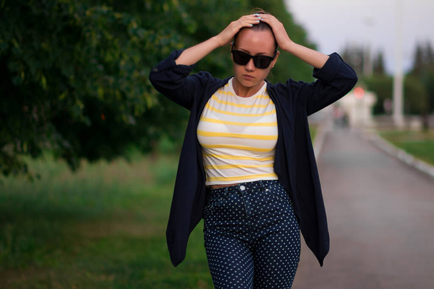 Selbstbewusste junge Frau mit Sonnenbrille auf Gehweg im Park - Foto, Bild