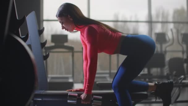Female student is doing exercise with dumbbell in the gym - Footage, Video