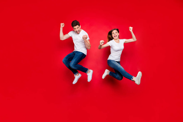 Full length body size photo of cheerful positive jumping excited rejoicing overjoyed girlfriend boyfriend wearing jeans denim white t-shirt footwear screaming yes yeah isolated vivid color background - Fotoğraf, Görsel