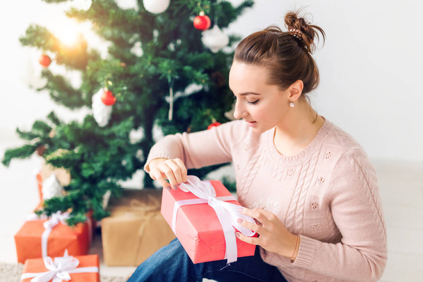 christmas, x-mas, winter, happiness concept - girl opens a gift against the background of the Christmas tree. Happy young woman celebrating Christmas - Fotoğraf, Görsel
