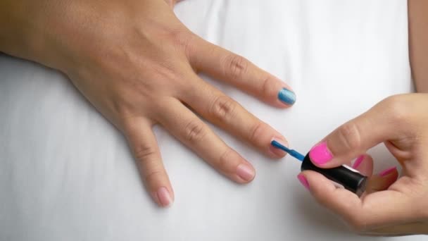 Nahaufnahme weiblicher Hände beim Bemalen von blauem Nagellack, selbstgemachte Maniküre zu Hause. - Filmmaterial, Video