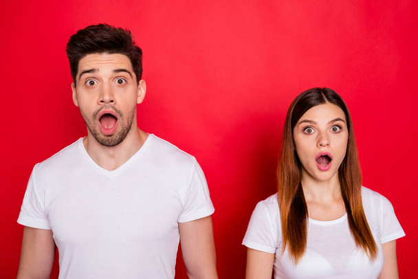 Photo of scared atonished couple of friends afraid of fake bad news spreading with mouth open wide expressing fear on faces with stubble on male face white t-shirt isolated vivid color background - Photo, Image