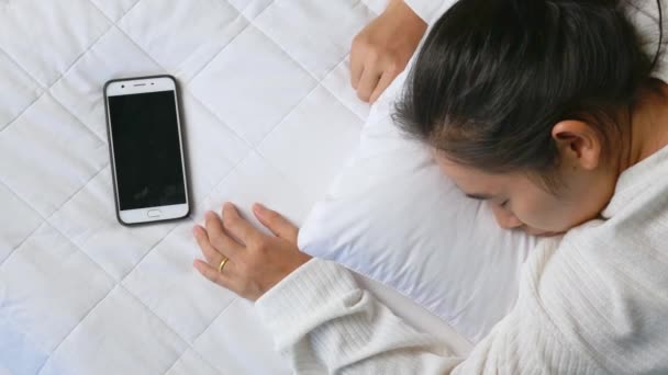 Azjatka sypiająca ze smartfonem w łóżku. Koncepcja technologii i opieki zdrowotnej. - Materiał filmowy, wideo