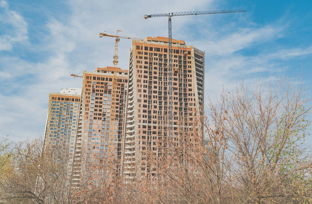 Výstavba výškových budov ve městě s věžovým jeřábem s zvedacím ramenem ve dne - Fotografie, Obrázek