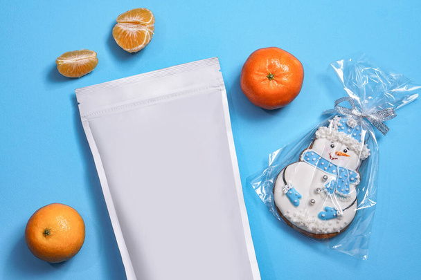 Modèle de sac écologique en papier pour le stockage du café, du thé avec des biscuits en forme de bonhomme de neige et des mandarines. Emballage sous vide pour Noël et nouvelle année présente
 - Photo, image