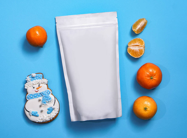 Modèle de sac écologique en papier pour le stockage du café, du thé avec des biscuits en forme de bonhomme de neige et des mandarines. Emballage sous vide pour Noël et nouvelle année présente
 - Photo, image