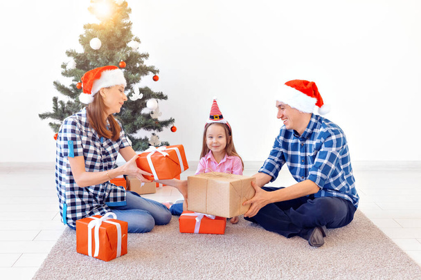 X-mas and holiday concept - Family opening christmas present in front of tree - Photo, Image