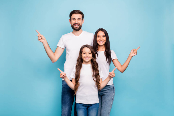 Portrait of positive cheerful three people promoters point at copy space recommend sales wear white t-shirt denim jeans isolated over blue color background - Foto, Imagem
