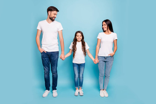 Full size photo of charming cheerful three people man and woman look at girl enjoy weekends holidays wear white t-shirt denim jeans stylish trendy sneakers isolated over blue color background - Valokuva, kuva
