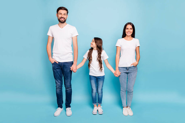 Full length photo of cheerful satisfied three people with brunette hair hold hand enjoy weekends wear white t-shirt denim jeans sneakers isolated over blue color background - Valokuva, kuva