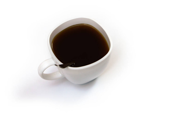 Biała filiżanka kawy z łyżką na odosobnionym tle. Czarny napój cappuccino w misce - Zdjęcie, obraz