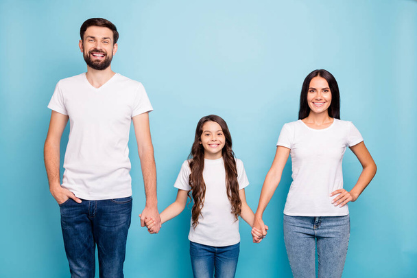 Portrait of cheerful content three people with wavy curly hair hold hand enjoy family weekends day wear white t-shirt denim jeans isolated over blue color background - Fotó, kép