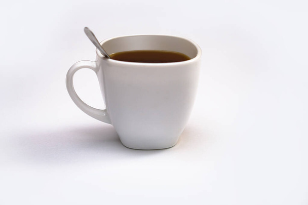 weiße Tasse Kaffee mit einem Löffel auf einem isolierten Hintergrund. schwarzer Cappuccino in einer Schüssel - Foto, Bild