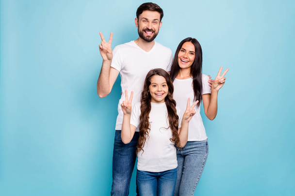 Portrait of candid three people promoters hug embrace have brunet hair make v-signs wear white t-shirt denim jeans casual outfit isolated over blue color background - Foto, Bild
