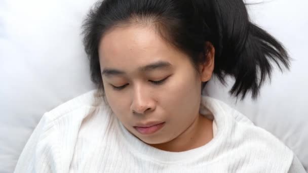 Asyalı kadın akıllı telefon kullanıyor ve sabahın erken saatlerinde yatakta esniyor. Teknoloji ve sağlık hizmetleri kavramları. - Video, Çekim