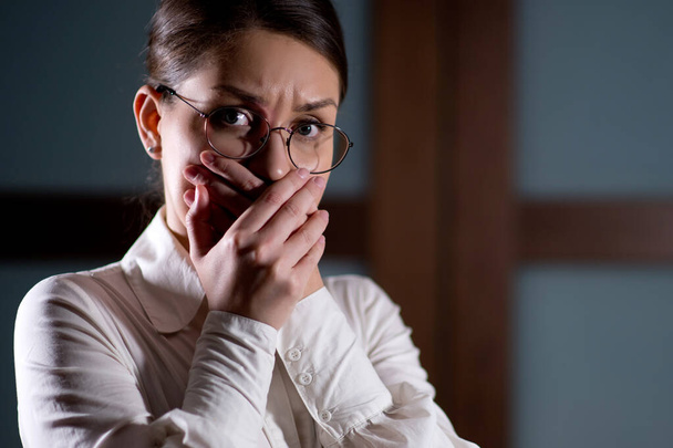 young woman in fear tightly covers her mouth with her hands - Foto, Imagem