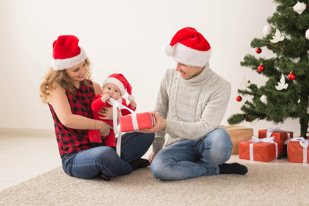Happy couple with baby celebrating Christmas together at home. - Фото, изображение