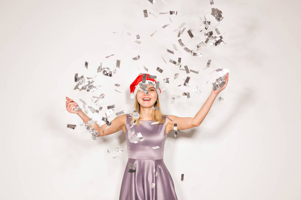 Nouvelle année et concept de vacances - Heureuse jeune femme excitée dans santa claus chapeau dansant et riant sur fond blanc
. - Photo, image