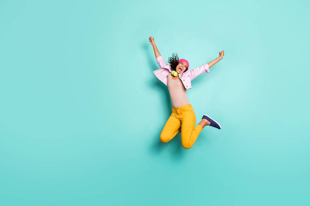 Повна довжина тіла фотографія насолодженої екстатичної радісної дівчини причинно-наслідковий стрибок кричить у смугастій футболці рожевий піджак головні убори жовті штани ізольовані яскраво-кольоровий фон бірюзовий
 - Фото, зображення