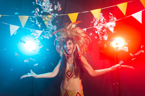 Καμπαρέ, χορεύτρια και γιορτές ιδέα-χαριτωμένο νεαρό κορίτσι σε φωτεινό πολύχρωμο καρναβάλι κοστούμι σε σκούρο φόντο - Φωτογραφία, εικόνα