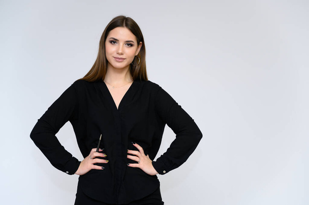 Close-up portrait of a young pretty girl secretary with long black hair in a business suit, on a white background. Standing right in front of the camera in different poses with emotions. - Фото, зображення