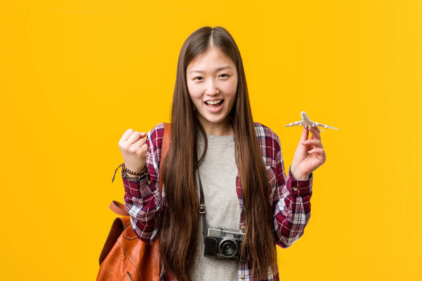 Young asian woman holding a airplane icon cheering carefree and excited. Victory concept. - Valokuva, kuva