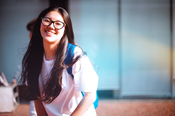 Hezká mladá asijská žena úsměv venku s lehkými úniky ze slunce v areálu školy. Šťastný student ve škole - Fotografie, Obrázek