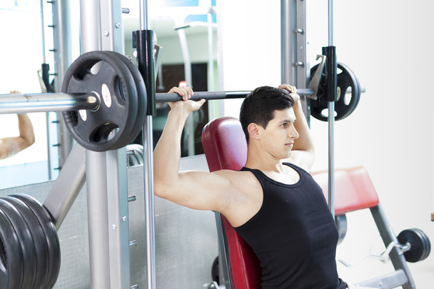 Handsome man lifting heavy weights at the gym - Foto, afbeelding